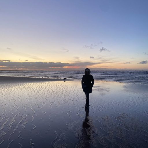 a female silhoeutte on a dark beach alone and cold